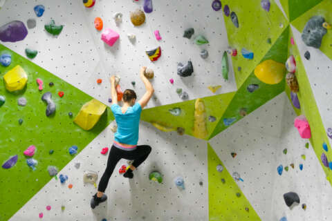 Junge Frau boulderd in Kletterhalle