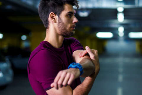 Junger Mann dehnt seine Schulter.