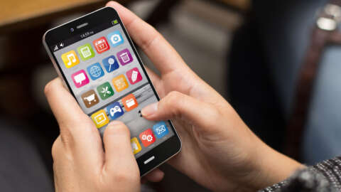 Gehirnjogging: Jemand hält ein Smartphone zwischen den Händen. und tippt auf die Apps auf dem Display