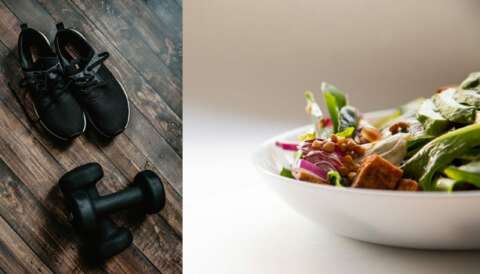 Schwarze Sportschuhe und Hanteln auf einem Holzboden und eine Schale mit Salat und Gemüse