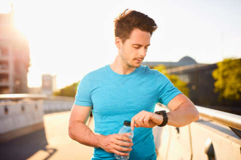 Junger männlicher Läufer checkt seinen Fitness-Tracker während seiner Laufrunde