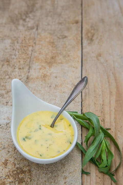 Spargel: Schale mit Sauce Béarnaise, Estragon und einem Löffel auf einem alten Holzuntergrund